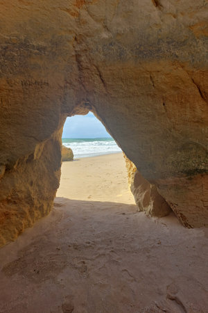 Natural sandstone arch on beach with ocean view. Scenic cave perspective photography for travel and tourism designの写真素材