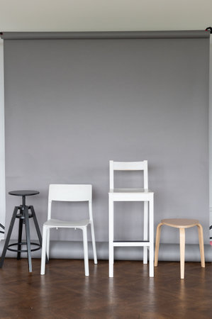 Explore the simplicity and elegance of modern interior design with a selection of stylish chairs set against a sleek gray backdropの写真素材