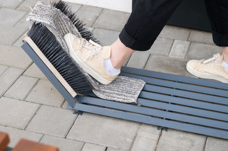 Close-up of a foot using a boot scraper on an outdoor doormatの写真素材