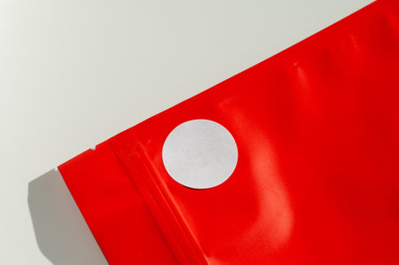 White circular sticker on red poly mailer envelope with natural shadow. Packaging and shipping concept for e-commerce and online retailの写真素材