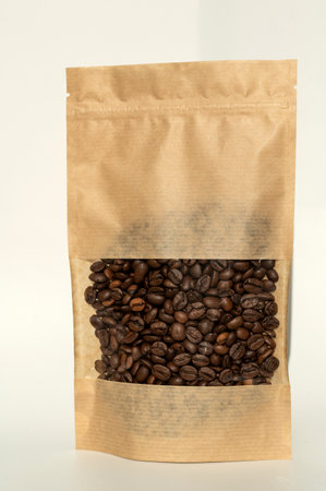 A brown kraft paper bag with a coffee bean lock for viewing with a highlighted shadow on a white background. Layout of the packaging template for food and essential goods.の写真素材
