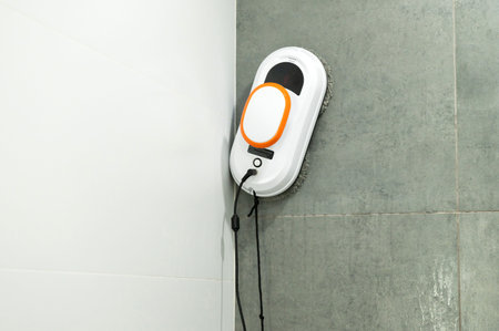 A sleek white and orange electric floor scrubber bustles along, efficiently polishing gray tiled flooring in a bright indoor spaceの写真素材