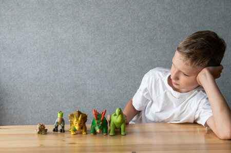 A thoughtful child engaging with a collection of colorful toy dinosaurs, evoking themes of playtime, imagination, and childhood curiosityの写真素材