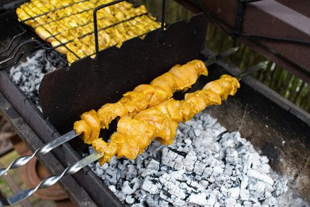 Delicious seasoned chicken satay skewers being grilled over hot coals, capturing the essence of outdoor cooking and barbecue flavorsの写真素材