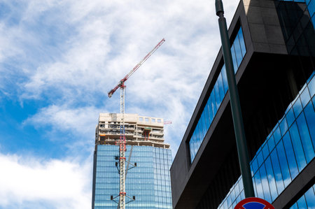 Skyscraper under construction with a crane on a blue sky background. Urban development and...