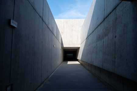A minimalistic concrete tunnel with light and shadow patterns, creating a stark and modern urban environment with an abstract feelの写真素材