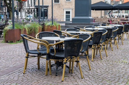Empty outdoor cafe tables and chairs in urban setting. City street photography with decorative plants. Design for banner, poster, postcard, headerの写真素材