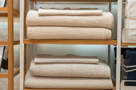 Stacks of white towels neatly arranged on metal shelves in retail store. Interior photography for design and store displayの写真素材