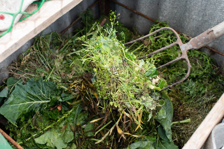 A close-up view of a garden fork lifting organic compost material in a sustainable home garden...