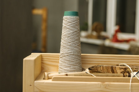 Artisan weaving spool with wooden tools for handmade craft projects.