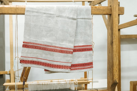 Traditional textile with red stripes on wooden loom display.の写真素材