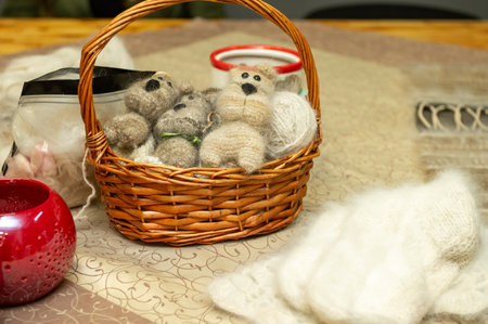 Wicker basket with handmade wool teddy bears and cozy decor on table.の写真素材