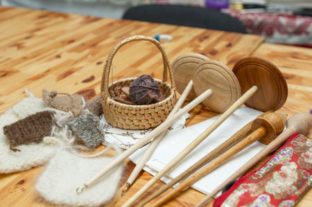 Handcrafted yarn tools and wool samples on wooden table.