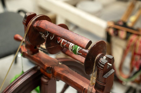 Wooden spinning wheel with yarn and hooks in workshop setting.の写真素材