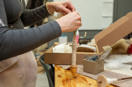 Female adult hand crafting yarn with spindle in workshop.の写真素材