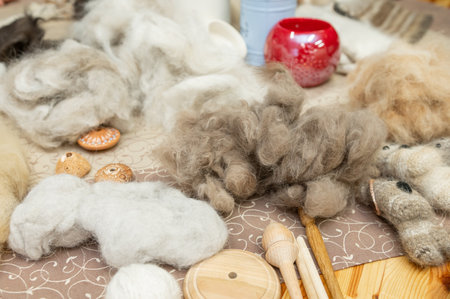 Wool fibers and tools for felting craft on patterned fabric background.の写真素材