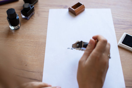 Close-up shot of a person's hand using a rubber stamp on a white document in an office environment,...