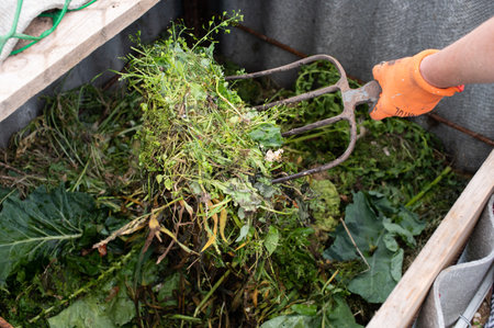 A close-up view of a garden fork lifting organic compost material in a sustainable home garden environmentの写真素材