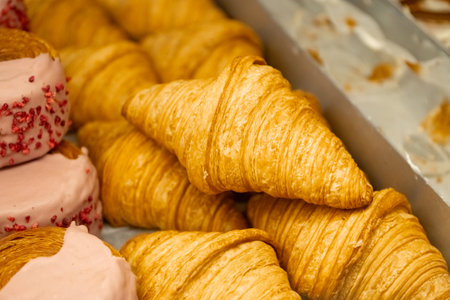 Golden flaky croissants stacked in a display tray. Close-up bakery food photographyの写真素材