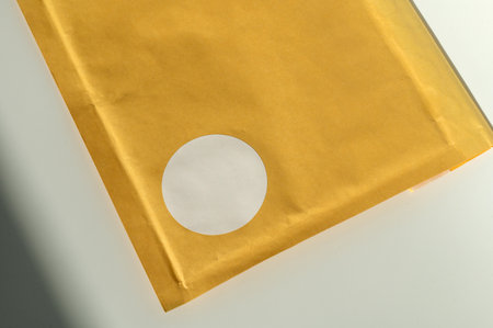 Brown padded envelope with white circular label on white surface.の写真素材