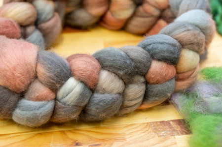 Close-up of multicolored wool roving in varied earth tones on a wooden surface.の写真素材