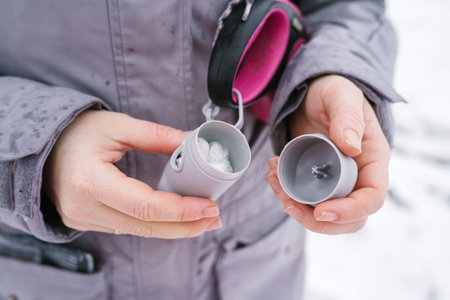 Caucasian adult female holding portable water filter in winter gear.