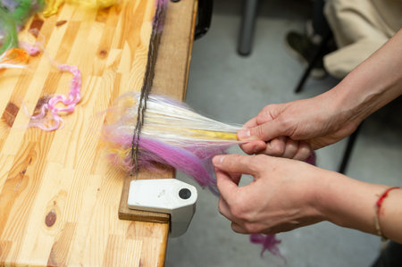 Crafting yarn: female hand combining colorful wool fiber on wooden table.の写真素材