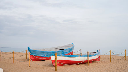 Colorful boats resting on sandy beach against cloudy sky.の写真素材