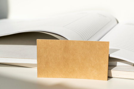 Brown paper card placed inside an open notebook. Stationery and office supplies concept.の写真素材