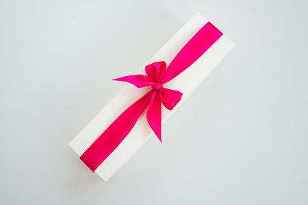 Rectangular gift box with pink ribbon on white background.の写真素材