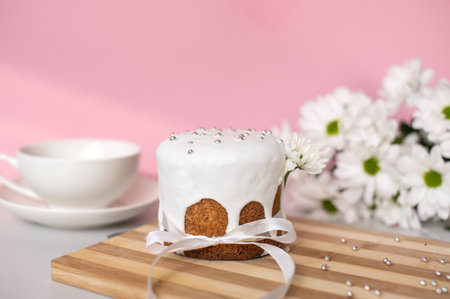 Decorated iced cake with white flowers and tea set on wooden board.の写真素材