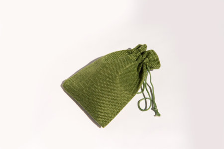 Green fabric drawstring bag on white background: elegant textured storage pouch.の写真素材