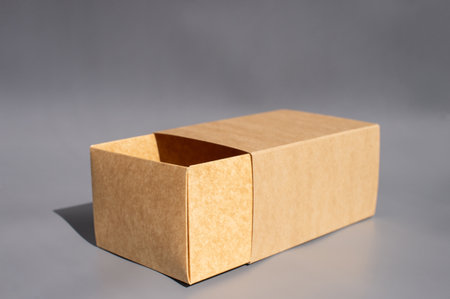 Open cardboard box on gray background with shadow effects.の写真素材