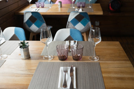 Elegant modern restaurant table setting with glasses and chairs.