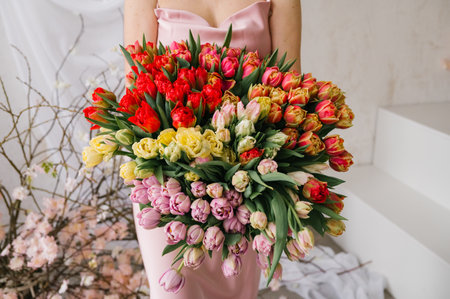 Female holding colorful tulip bouquet in pink dress.の写真素材