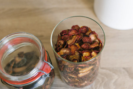 Two transparent glass jars filled with assorted dried fruits are neatly placed on a modern kitchen countertopの写真素材