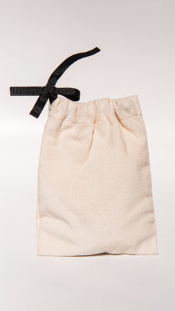 Cream drawstring pouch with black ribbon on white background.の写真素材