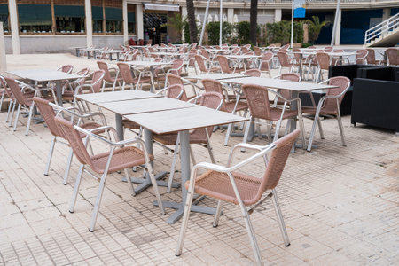 Empty outdoor cafe with pink chairs and tables on a patio.の写真素材