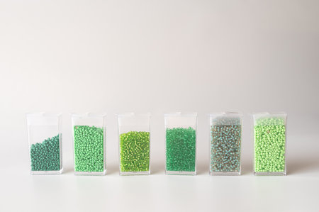 Set of transparent containers with green beads in gradients on white background.