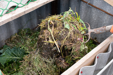An individual mixes nutrient-rich compost using a trowel as part of their home gardening activities,...