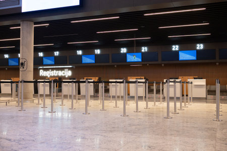 Empty airport check-in counter with sign and digital screens in modern terminal.