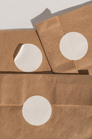 Blank circular stickers on brown paper bags with shadows.