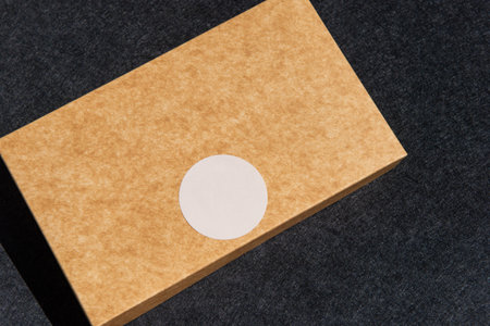 Brown box with white sticker on dark surface.の写真素材