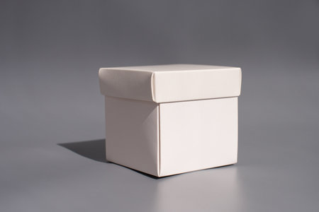 Minimalist white gift box on gray background in soft lighting.