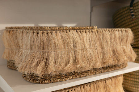 Handwoven fringe basket on white shelf with fiber texture and natural design.