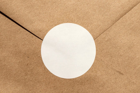 Brown envelope with circular white seal on kraft paper texture.の写真素材