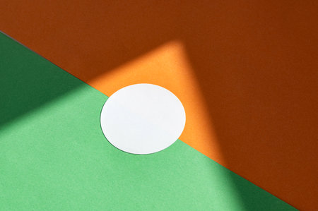 Abstract minimalist design with white circle on green and orange background.の写真素材
