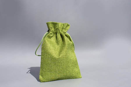 Green textured drawstring bag on gray background - eco-friendly fabric pouch.の写真素材