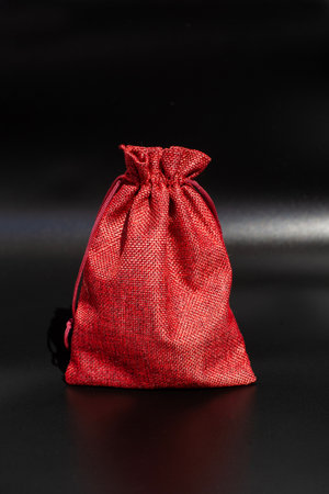 Red fabric drawstring bag on black background.の写真素材