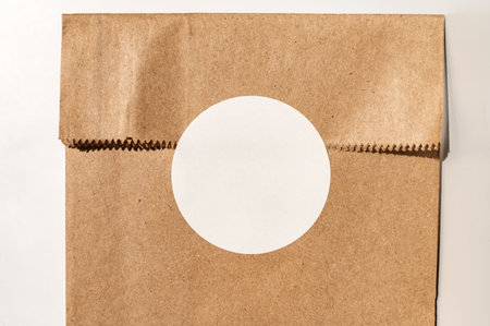 Blank circle sticker on brown paper bag for branding or packaging design.の写真素材